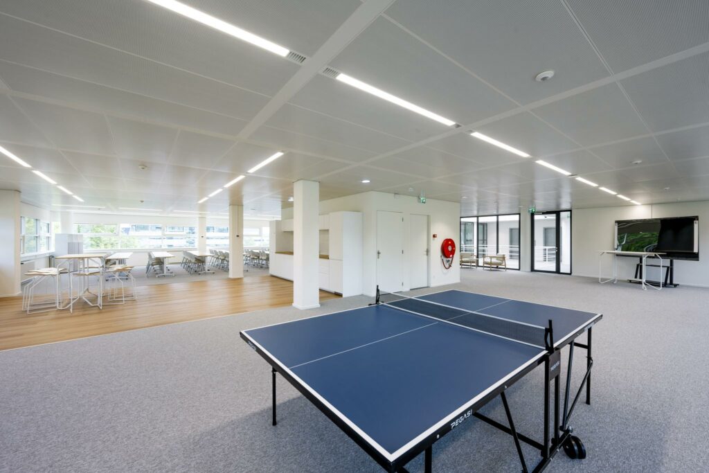 Moderne kantoorruimte aan de Burgemeester Stramanweg met tafeltennistafel, vergadertafels en een groot presentatiescherm.